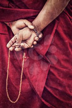 Vintage retro effect filtered hipster style travel image of Tibetan Buddhism - prayer beads in Buddhist monk hands with grunge texture overlaid. Ladakh, India