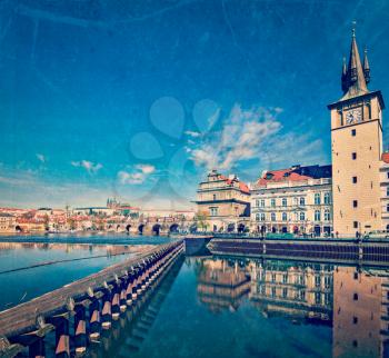 Vintage retro hipster style travel image of Prague Stare Mesto embankment view from Charles bridge with grunge texture overlaid. Prague, Czech Republic