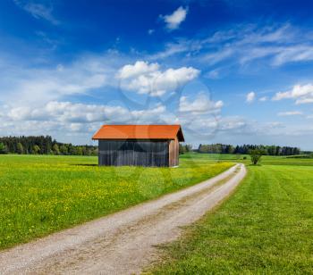 Rural road in summer meadow with wooden shed. Bavaria, Germany
