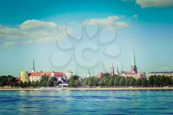 Vintage retro hipster style travel image of 
View of Riga over Daugava river: Riga Castle, St. James's Cathedral, St. Peter's Church. Riga, Latvia