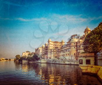 Vintage retro hipster style travel image of romantic India luxury tourism concept background - Udaipur City Palace and Lake Pichola. Udaipur, Rajasthan, India with grunge texture overlaid