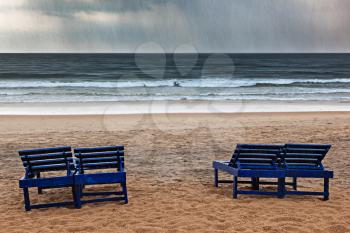 Beach chairs under rain and stormy sea