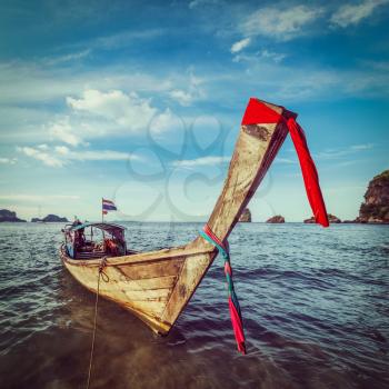 Vintage retro hipster style travel image of Thai Long tail boat on sunset, Krabi, Thailand