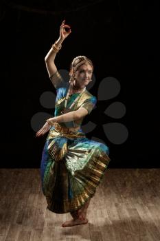 Vintage retro style image of young beautiful woman dancer exponent of Indian classical dance Bharatanatyam in Shiva pose