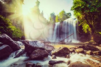 Vintage retro effect filtered hipster style image of tropical waterfall with sun rays in Cambodia