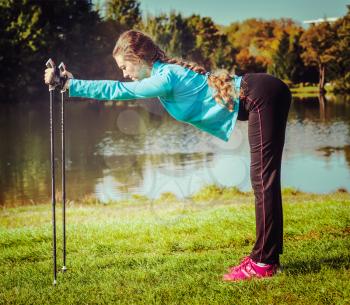 Vintage retro effect filtered hipster style image of nordic walking adventure and exercising concept - woman doing exercise with nordic walking poles in park