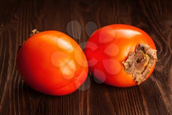 Two fresh ripe orange  persimmon on a wooden background