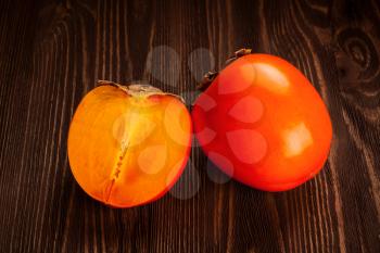 Fresh ripe orange persimmon and slice on a wooden background