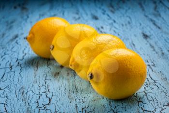 Four fresh ripe yellow lemons on blue wooden background