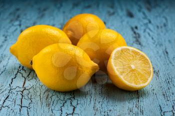 Five fresh ripe yellow lemons on blue wooden background