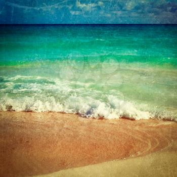 Vintage retro hipster style travel image of beautiful beach and  waves of Caribbean Sea with grunge texture overlaid