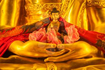 Small Buddha Sakyamuni statue in hands of large Buddha in Tibetan Buddhist temple. Himachal Pradesh, India