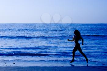 Healthy life concept - sporty woman running along beach in the morning