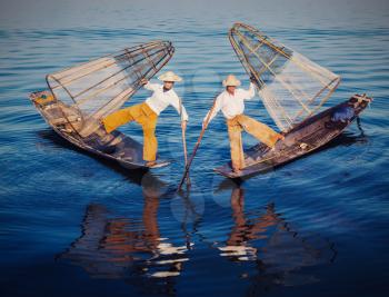 Myanmar travel attraction - Traditional Burmese fishermen balancing with fishing nets at Inle lake in Myanmar. Vintage filtered retro effect hipster style image