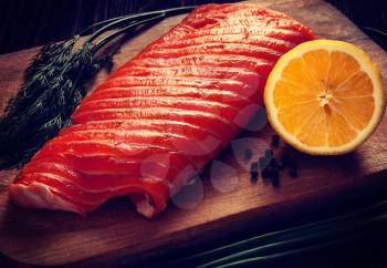 Vintage retro effect filtered hipster style image of fresh salmon piece on wooden cooking board with vegetables