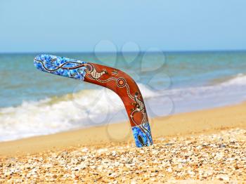 Boomerang on Sandy Beach Against of Sea Surf.