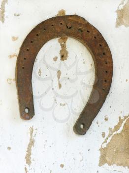 Old lucky horseshoe on aged white clay wall background.