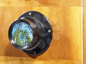 Old camera lens with green forest inside.