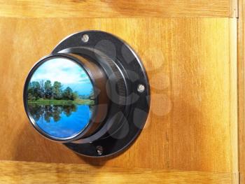 Old camera lens with picturesque landscape inside.