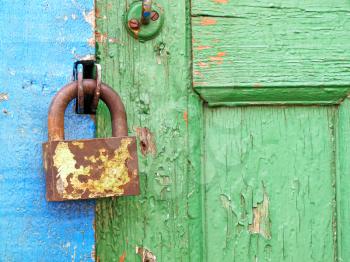 Old metal lock on a aged color wooden door taken closeup.