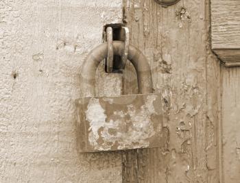 Old metal lock on a wooden door taken closeup.