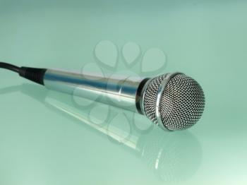 Silver metallic microphone on a transparent blue background.