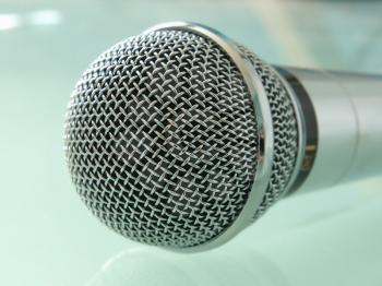 Metallic microphone taken closeup on a blue background.