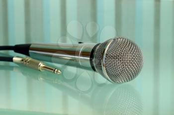 Metallic microphone on a striped transparent surface taken closeup. 