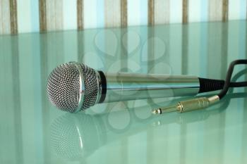 Metallic microphone on a transparent table taken closeup. 