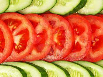 Sliced tomatoes and cucumbers taken closeup as background.