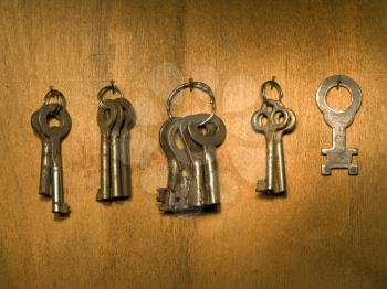 Bunches of old keys on a wooden wall surface.