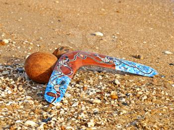 Colorful boomerang and coconut on a sandy beach.