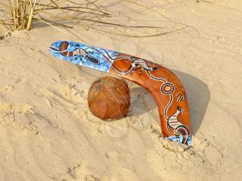 Colorful boomerang and coconut on a sand.