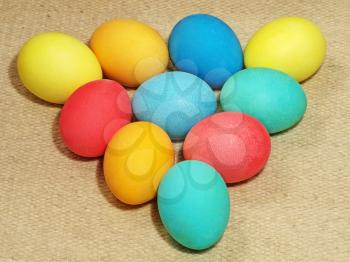 Multicolored easter eggs arranged in a triangle on a wool background.