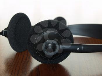Black  headset on a wooden table taken closeup.