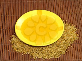 Honey in yellow plate and flower pollen on a wooden surface.