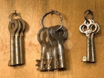 The bunches of old rusty keys on a wooden surface.