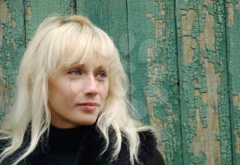 Pretty blonde against grunge green wooden wall.
