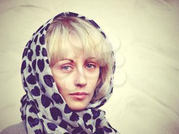 Pretty blonde in a spotty scarf against white clay wall.