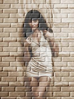 Cute brunette on a brick wall grunge background.Digitally generated image.
