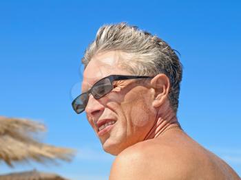 Portrait of a adult man in glasses against of blue sky.