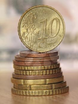 Ten euro cent coin balancing on a top of coins stack taken closeup.