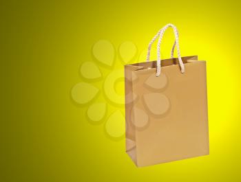 Empty golden shopping bag on a yellow background.