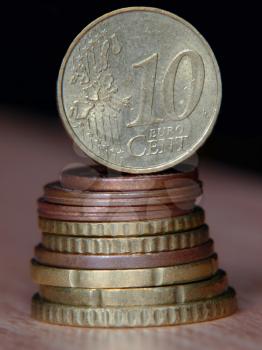 Ten euro cent coin balancing on a top of coins pile taken closeup.
