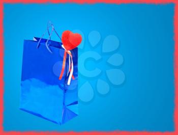Blue Valentines Day gift bag and red heart on blue background with red frame border.