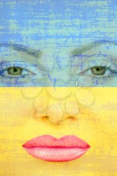 Pretty woman face with tear on Ukranian flag background.Crying Ukraine.