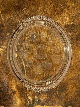 Golden oval photo frame with empty space inside on grungy wall taken closeup.