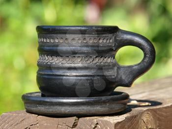 Old black arabian ceramic cup taken closeup on green background.