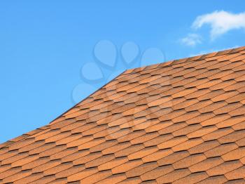 Roof of bituminous tiles taken closeup against of blue sky.