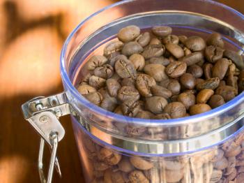 Appetizing coffee beans in glass container taken closeup.